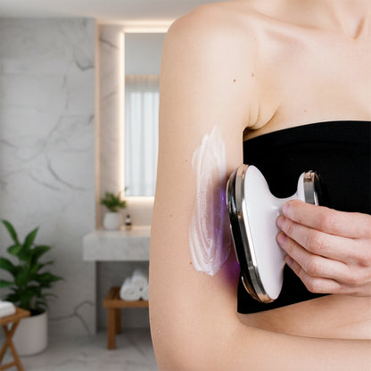 crème sur bras de femme avec appareil de massage dans la main dans la salle de bain