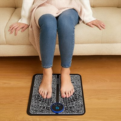 femme les pieds sur appareil de massage gris dans le salon