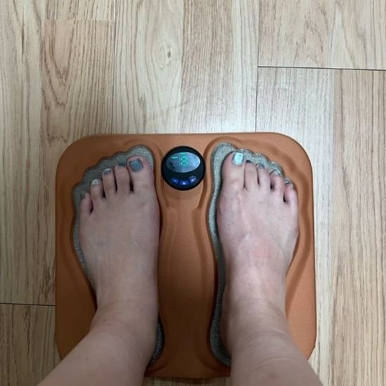  pied avec ongle orteil gris sur appareil de massage brun sur plancher bois