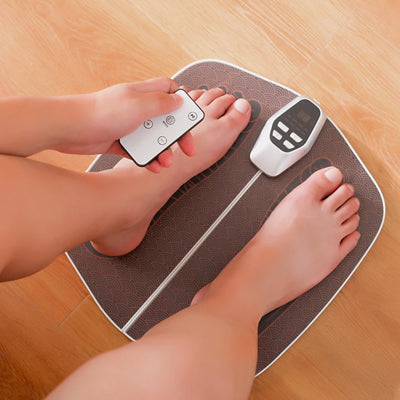 télécommande dans la main appareil massage pieds sur plancher bois