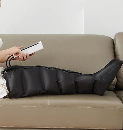 femme avec télécommande dans les main bottes pressothérapie sur sofa beige fond blanc 