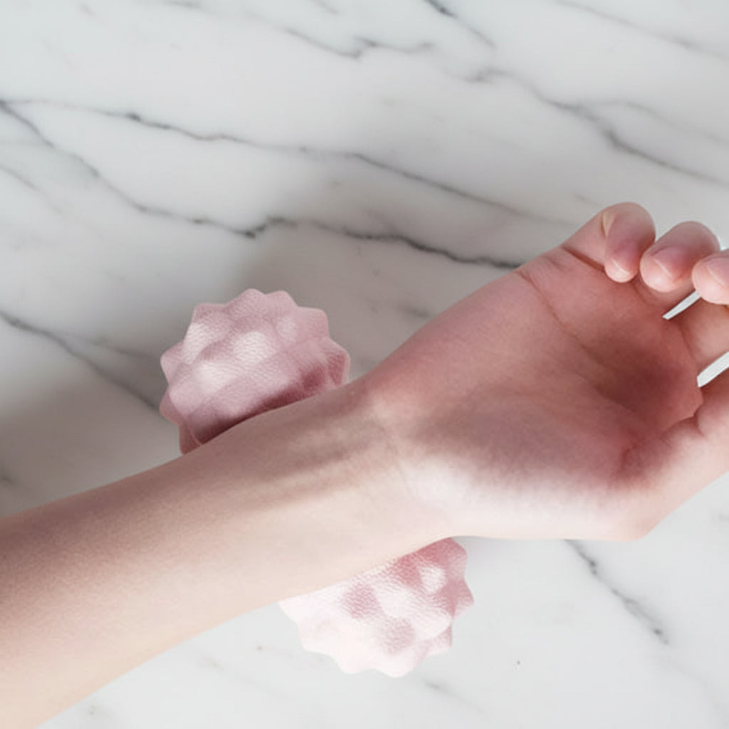 main sur boule de massage rose sur table de marbre