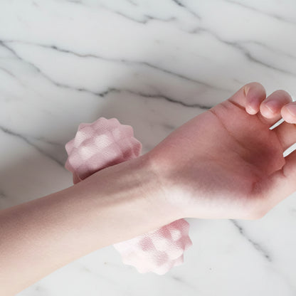 main sur boule de massage rose sur table de marbre