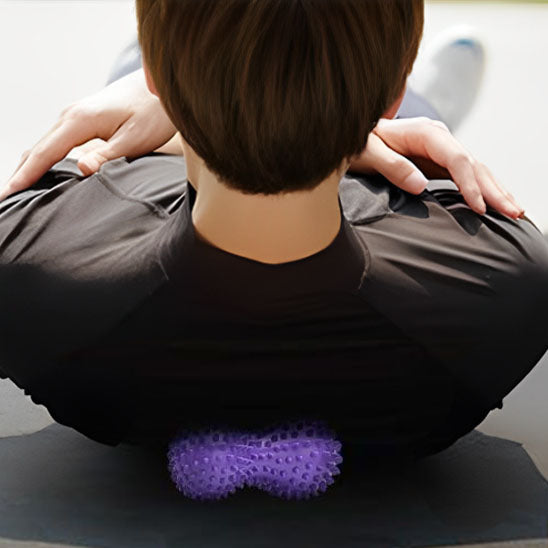 homme en gilet noir sur boule de massage violet sur tapis gris