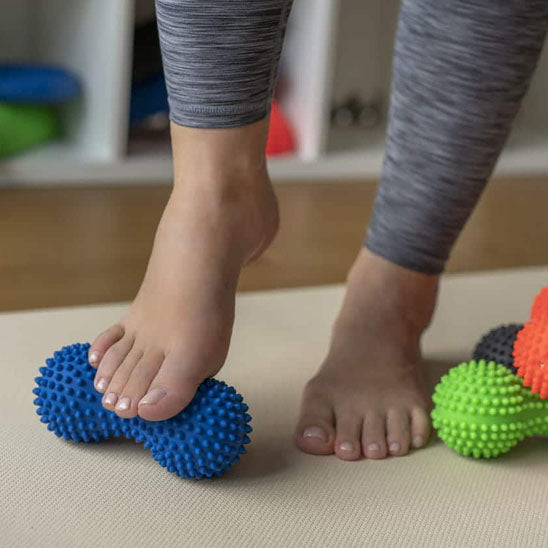 pieds sur boule de massage bleu et tapis beige dans un gymnase