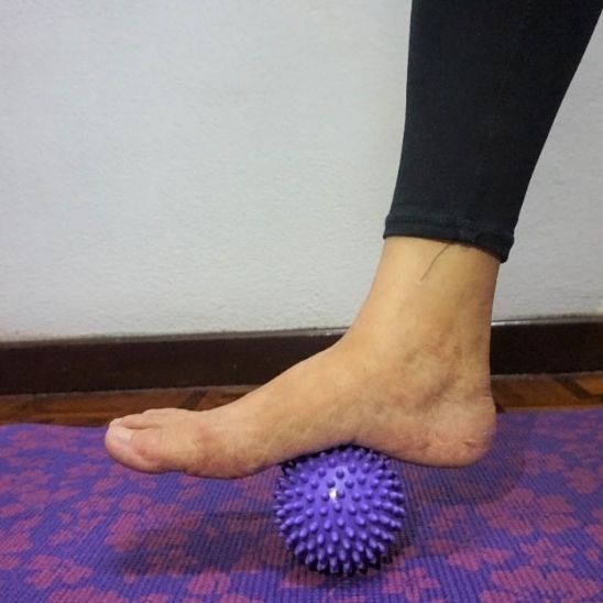 pied de femme sur boule de massage bleu sur tapis fleuri bleu rose