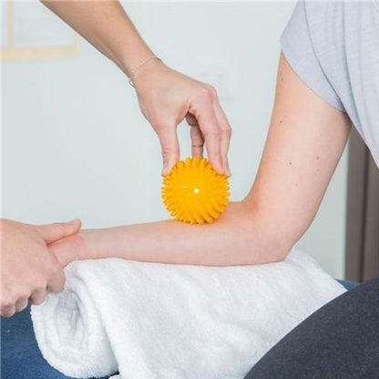 main sur  boule de massage jaune sur bras salle de massage