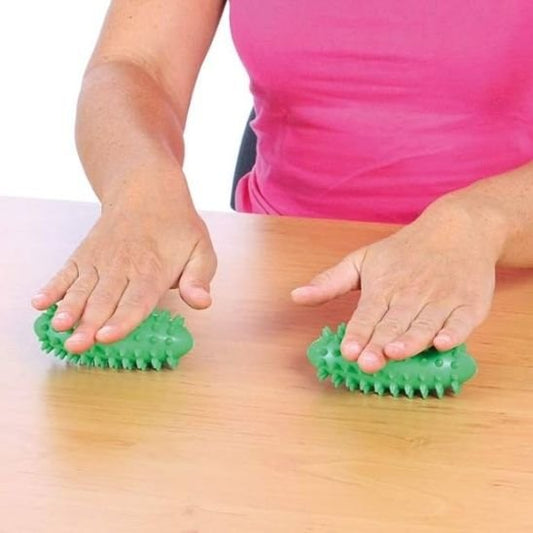 roule deux boule de massage vert sous ses mains sur table bois
