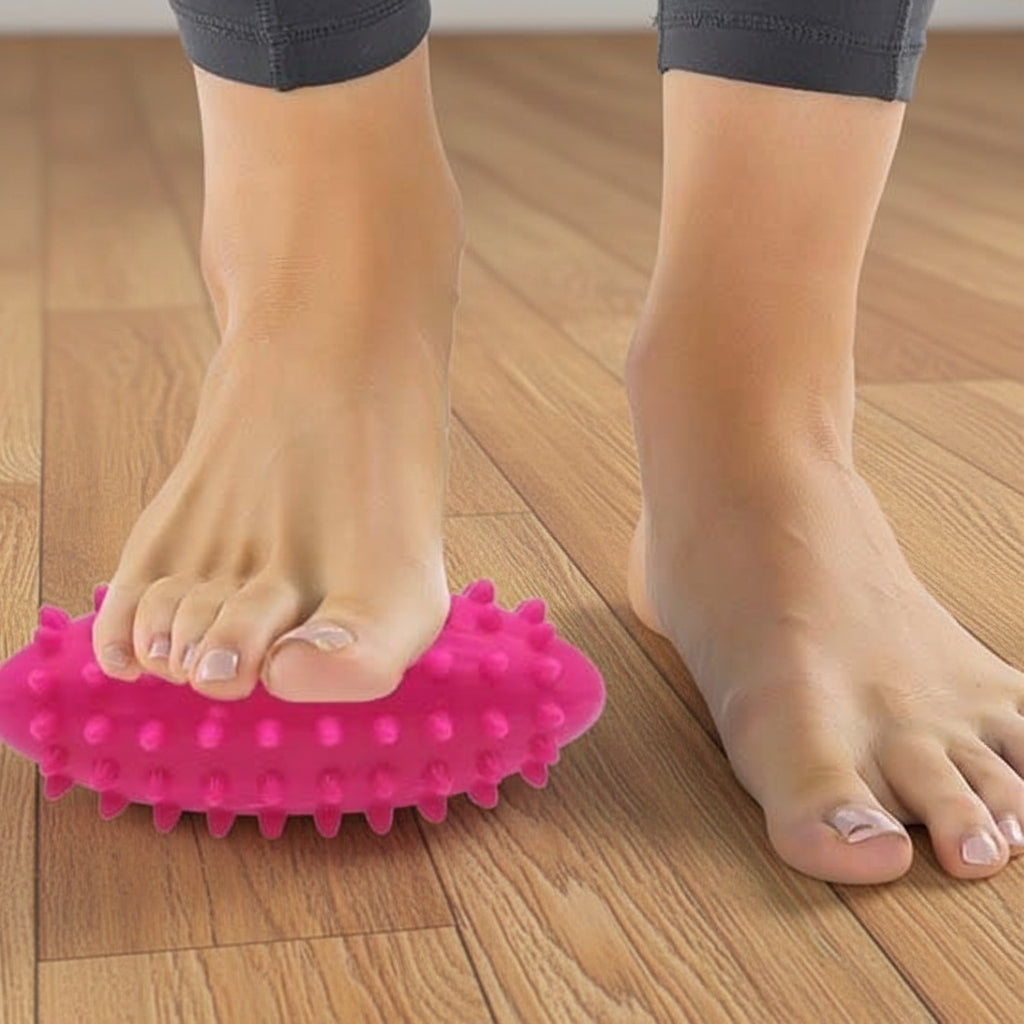 pied sur boule de massage rose sur plancher de bois