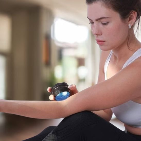 main de femme en camisole blanche  avec boule de massage noir dans salle de bain 