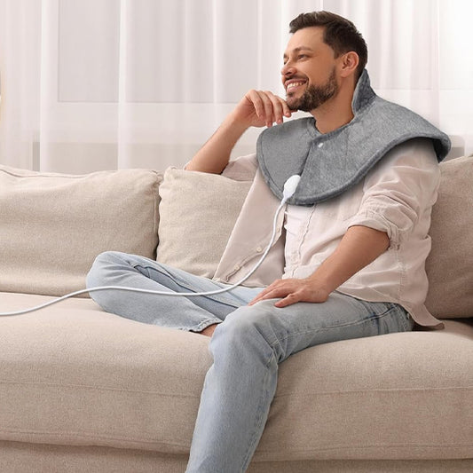 coussin chauffant sur épaule d'un homme devant une grande fenêtre