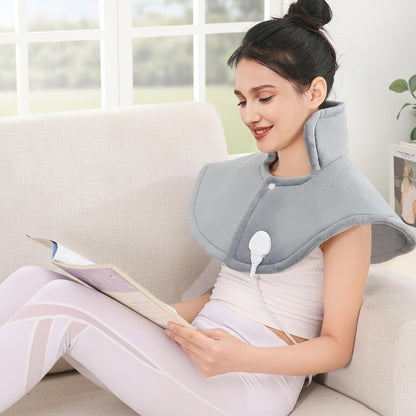 femme avec coussin chauffant sur les épaule devant une grande fenêtre