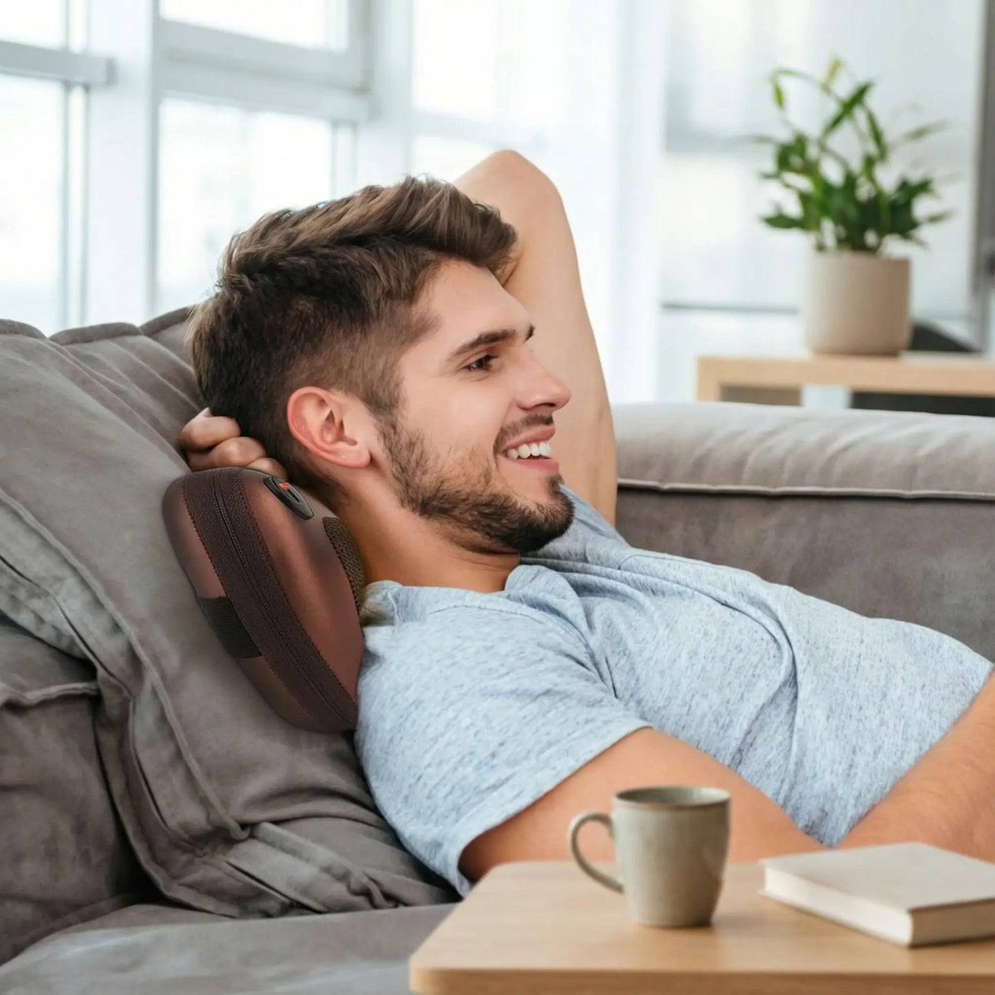 homme le cou sur coussin chauffant sur le sofa avec son café