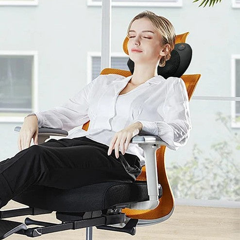 femme en blouse blanche le cou sur coussin chauffant devant une grande fenêtre