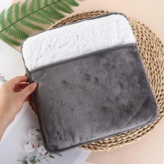 Main sur Coussin Chauffant pour Pieds sur un tapis d'osier