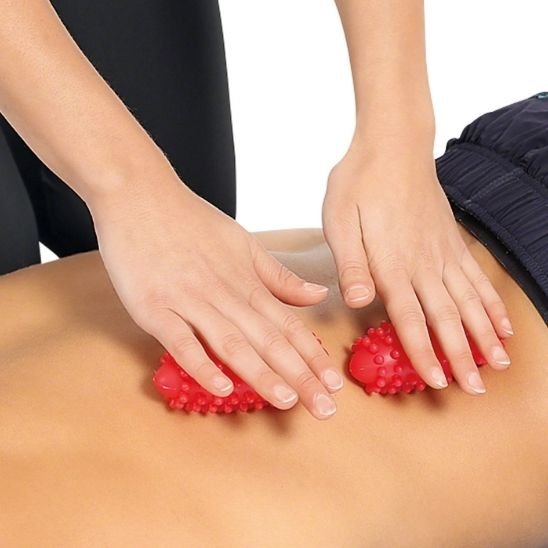 deux main roule boule de massage rouge sur dos nu