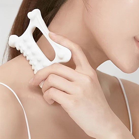 femme la main sur gua sha sur épaule fond blanc