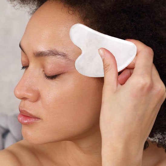 gua sha blanc sur le front fond flou