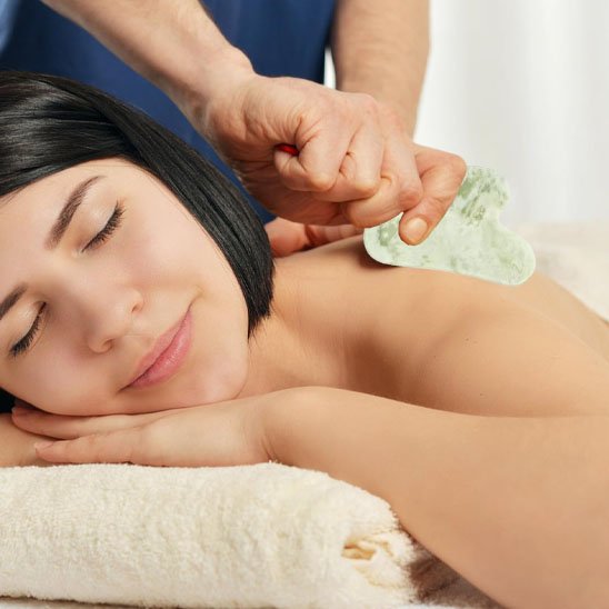 gua sha sur l'épaule sur une table de massage fond flou