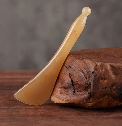 gua sha tendon appuyer sur une buche sur une table en bois