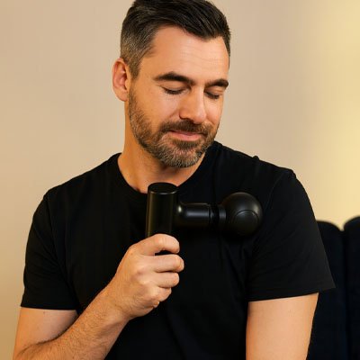 homme en noir pistolet de massage noir epaule