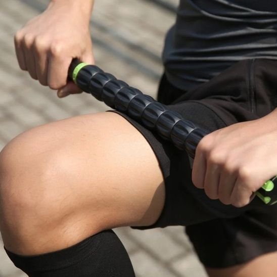 homme en noir roule rouleau de massage noir cuisse