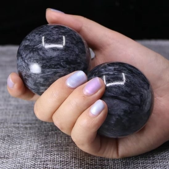 main tiens deux boule de massage noir sur tapis gris