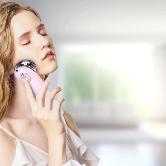 femme avec masseur visage devant une fenêtre flou