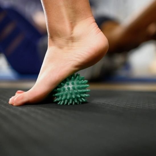 pied sur boule de massage vert sur surface noir