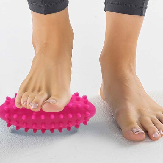 pied sur plancher blanc et boule de massage rose dessous autre pied