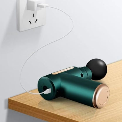 pistolet de massage musculaire vert sur une table de bois fil au mur blanc