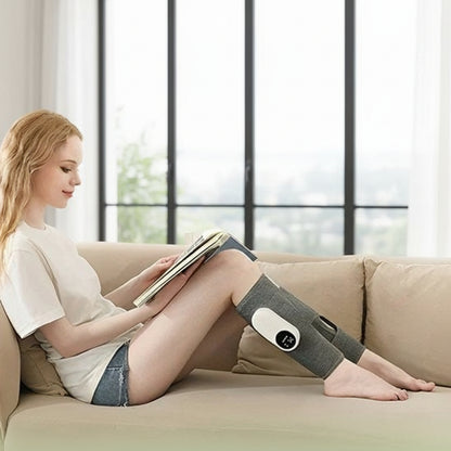 femme en gilet blanc sur sofa brun avec pressothérapie pour les jambes devant une grande fenêtre