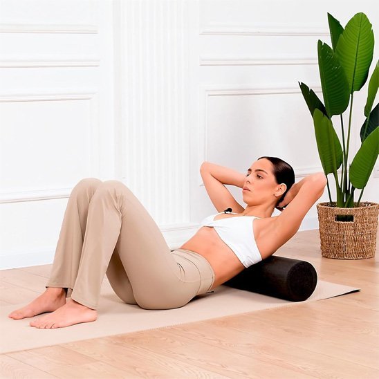 femme en top blanc rouleau de massage noir dans le salon