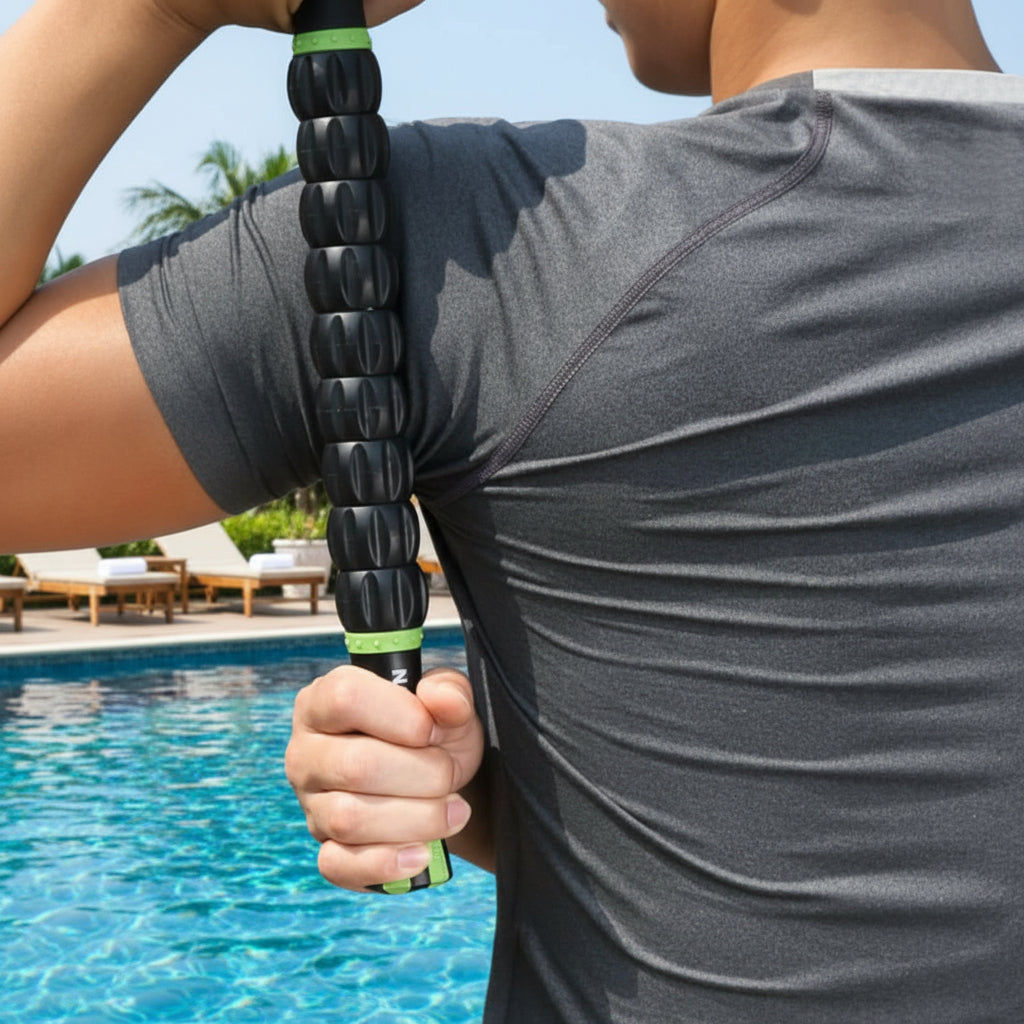 main sur rouleau de massage noir sur homme en teeshirt gris au bord de la piscine