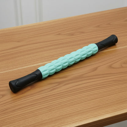 rouleau de massage vert et noir sur une table en bois