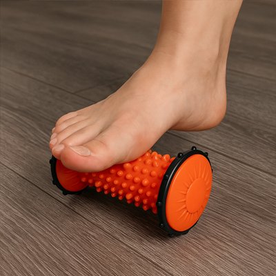 pied sur rouleau de massage orange sur plancher de bois 