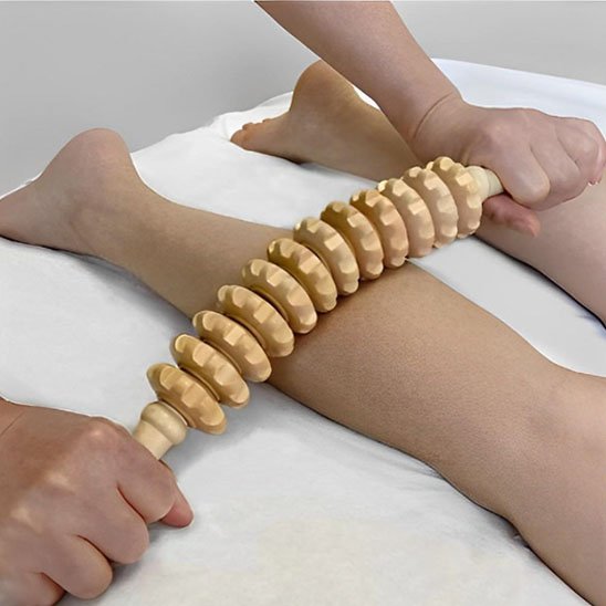 les mains sur rouleau de massage sur   les jambes sur une table de massage