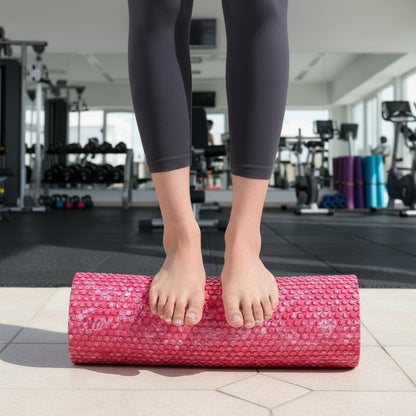 pieds de femme en pantalon noir sur rouleau de massage rose dans une salle de gymnase