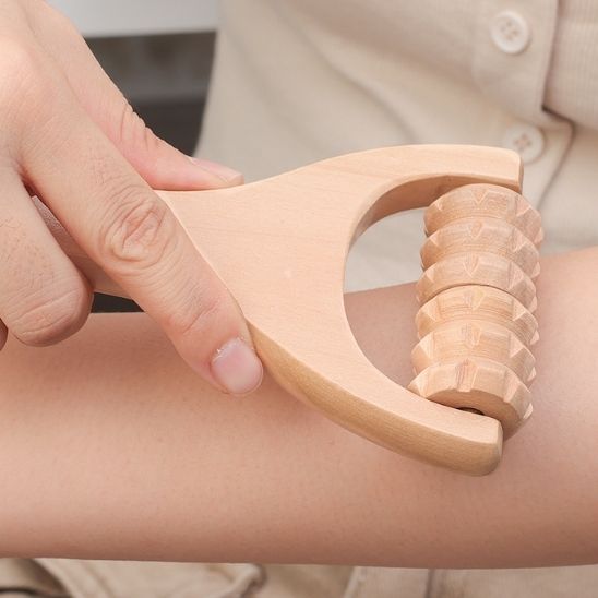 Main sur rouleau de massage en bois sur bras fond flou