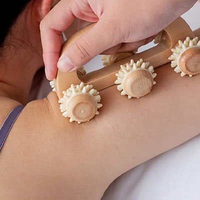 main sur rouleaux de massage en bois sur épaule femme fond blanc