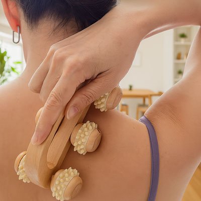 main sur rouleaux de massage en bois sur dos de femme avec bretelle bleu salle de séjour