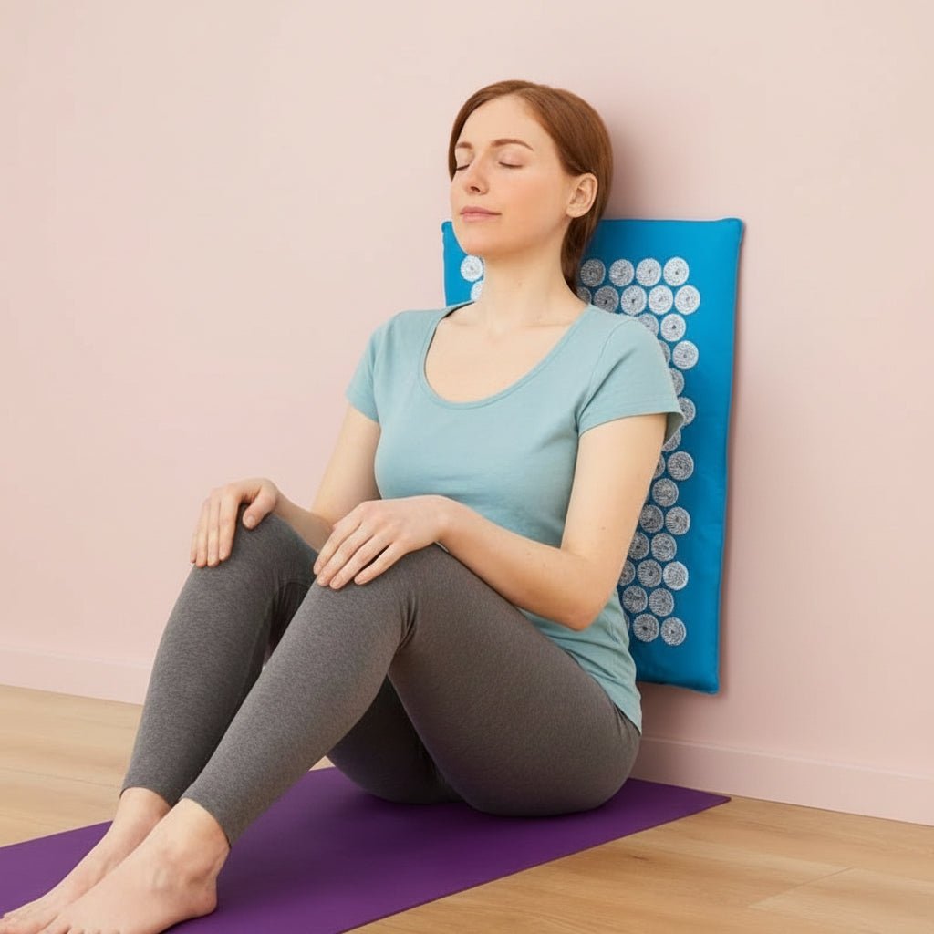 Femme assis le dos sur tapis d'acupression bleu et tapis violet sur plancher de bois