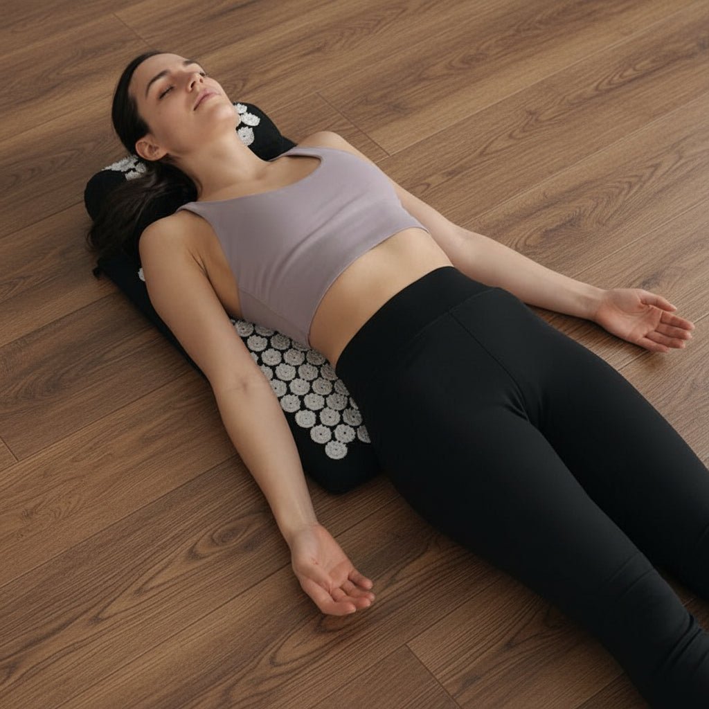 Femme en camisole violet et pantalon noir sur tapis d'acupression noir sur fond gris